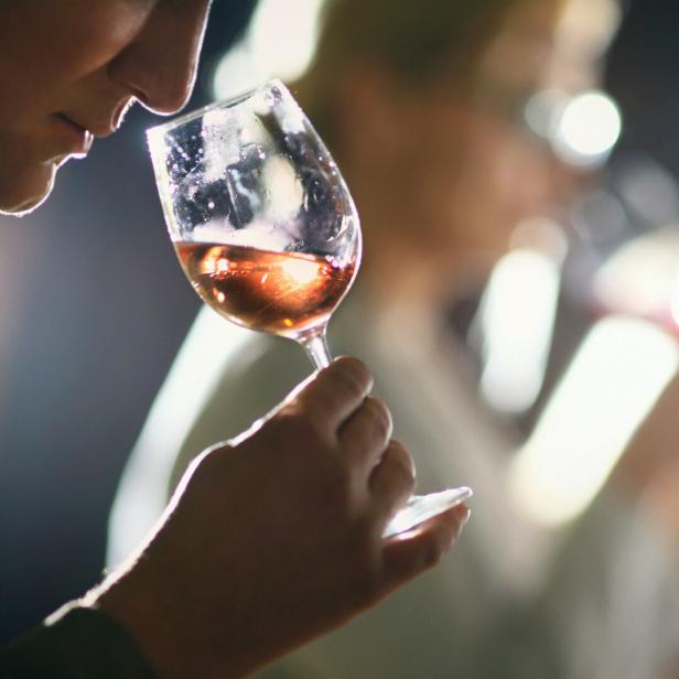 Ein Mann riecht an einem Glas Roséwein.