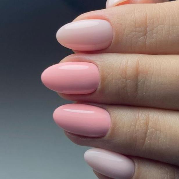 Nahaufnahme von Fingernägeln mit rosa Lack in verschiedenen Farbtönen.