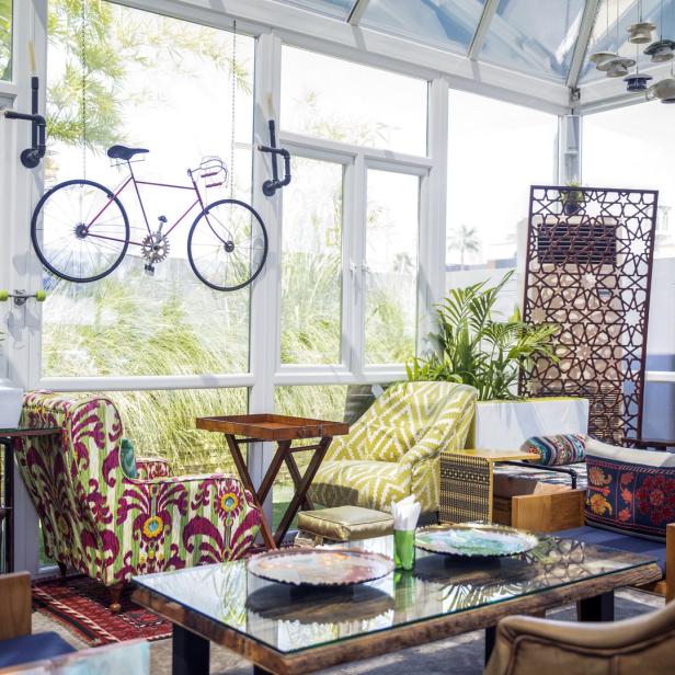 Ein helles Interieur mit verschiedenen Sitzgelegenheiten, Pflanzen und einem dekorativen Fahrrad an der Wand.