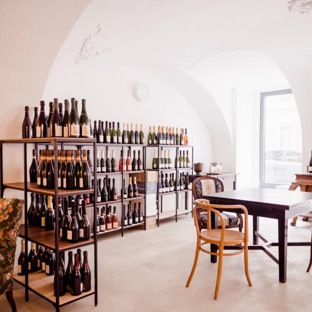 Ein Weinladen mit Regalen voller Weinflaschen und einem Tisch mit Stühlen.