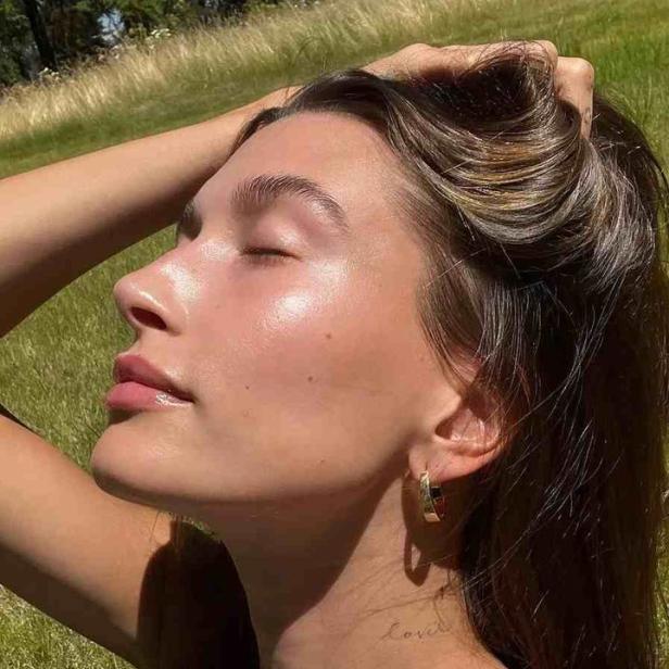 Eine Frau mit geschlossenen Augen genießt die Sonne auf einer Wiese.