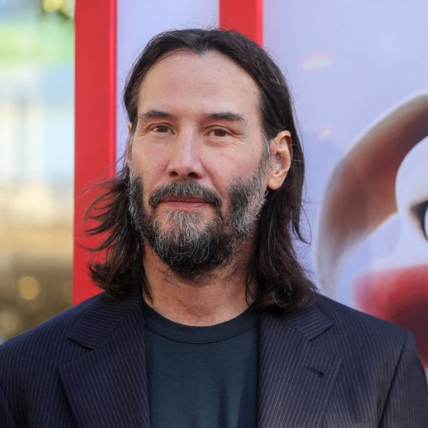 Keanu Reeves posiert vor einem Poster des Films „All Pets Allowed“.