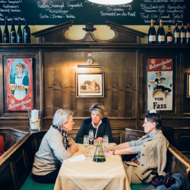 Gäste sitzen in einem traditionellen Wiener Restaurant an Tischen.