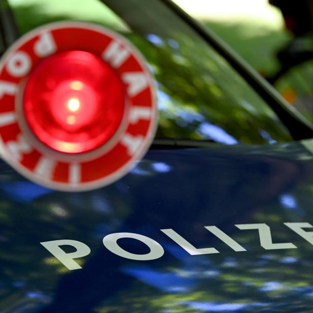 Ein rotes Blinklicht und der Schriftzug „Polizei“ auf einem blauen Autodach.