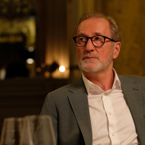 Ein Mann mit Brille und Anzug schaut nachdenklich zur Seite.