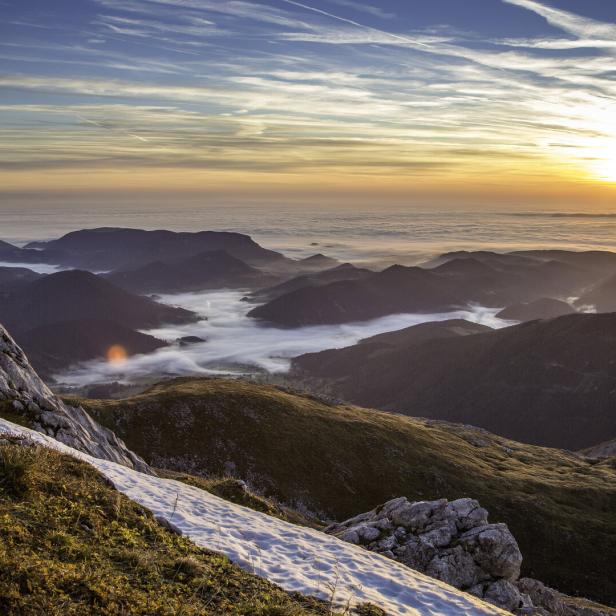 Sonnenaufgang über einer Berglandschaft mit Nebel in den Tälern.