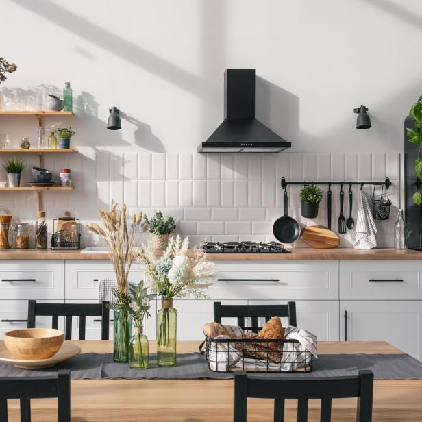 Eine moderne Küche mit Holztisch, weißen Schränken und einem schwarzen Kühlschrank.