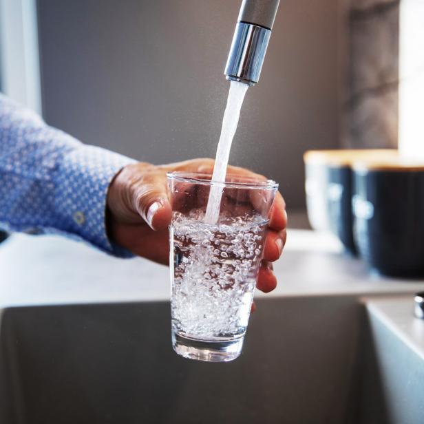 Wasser fließt aus dem Wasserhahn in ein Glas.