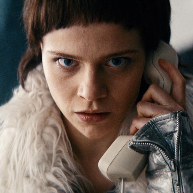 Eine Frau mit ernstem Blick telefoniert mit einem alten Telefonhörer.