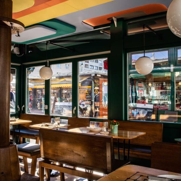 Innenansicht eines Restaurants mit Holzbänken und Blick auf die Straße.