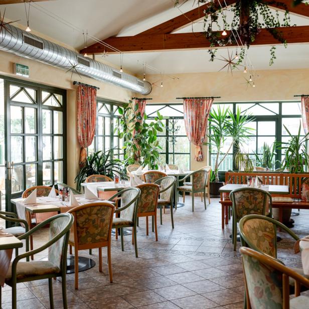 Ein Restaurantraum mit gedeckten Tischen und vielen Pflanzen.