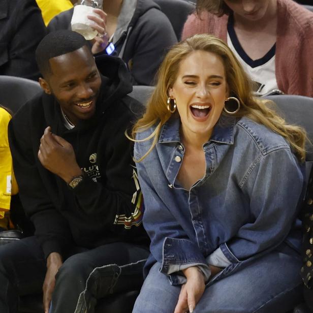 Adele lacht mit einem Mann bei einem Basketballspiel.