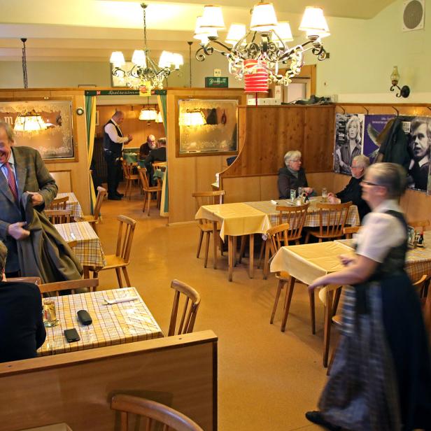 Ein belebtes Restaurant mit Gästen und einer Kellnerin in Tracht.