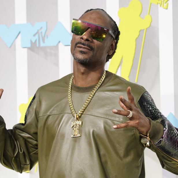 Snoop Dogg mit Sonnenbrille und goldener Kette auf dem roten Teppich.