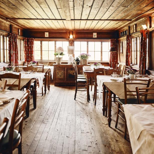 Ein Speisesaal mit Holzwänden, Tischen mit weißen Tischdecken und Blumenarrangements.