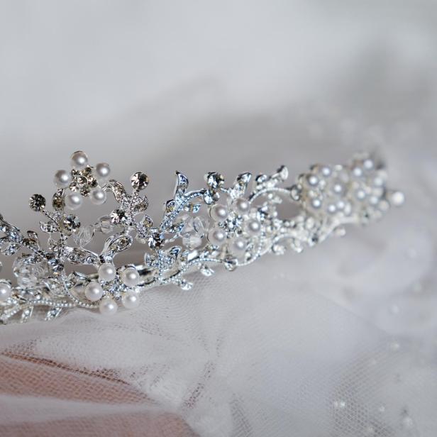 Eine silberne Tiara mit Perlen und Strasssteinen liegt auf einem Schleier.