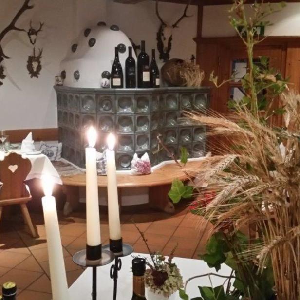 Ein festlich gedeckter Tisch in einem traditionellen bayerischen Gasthof mit Kachelofen und Geweihschmuck.