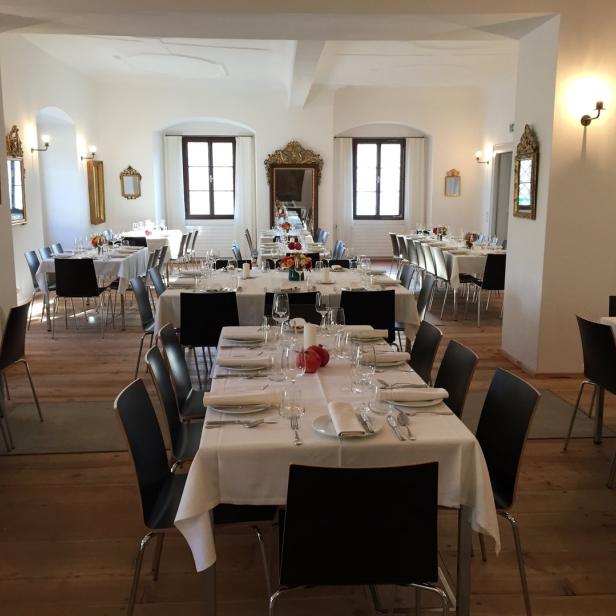 Ein festlich gedeckter Saal mit Tischen und Stühlen für eine Veranstaltung.
