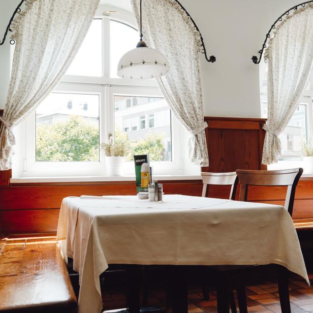 Ein Tisch mit weißer Tischdecke in einem hellen Restaurant mit Holzvertäfelung.