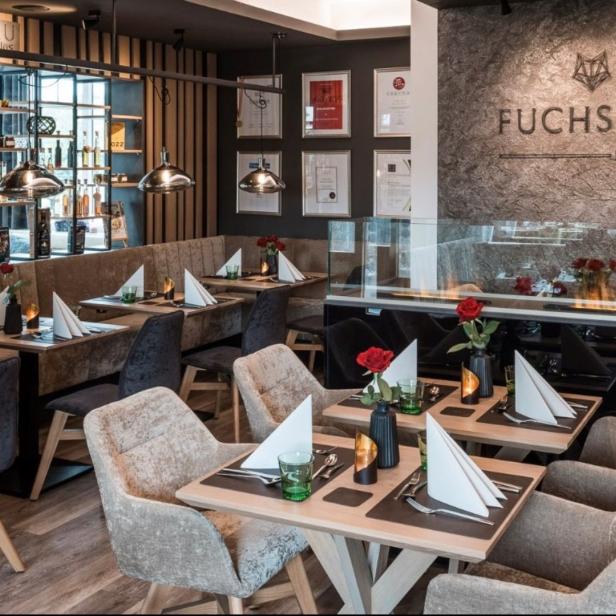 Innenansicht des Restaurants „Fuchsbau“ mit gedeckten Tischen und moderner Dekoration.