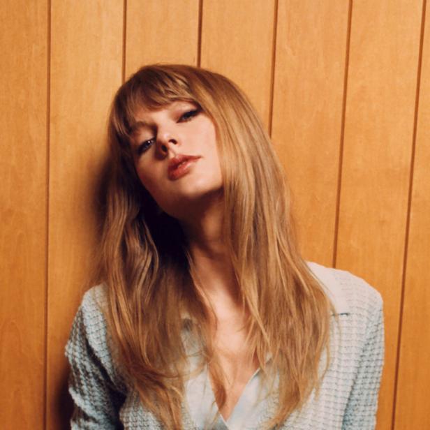 Taylor Swift posiert vor einer Holzwand.