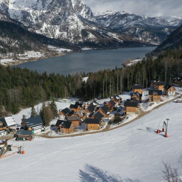 Blick auf ein verschneites Skidorf in den Bergen mit einem See im Hintergrund.