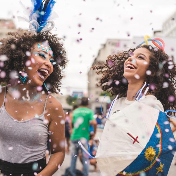 Zwei lachende Frauen feiern mit Konfetti auf der Straße Karneval.