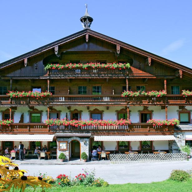 Ein traditionelles bayerisches Haus mit blumengeschmückten Balkonen und einem Restaurant im Erdgeschoss.