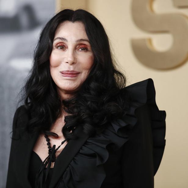 Cher posiert in einem schwarzen Blazer mit Rüschen.