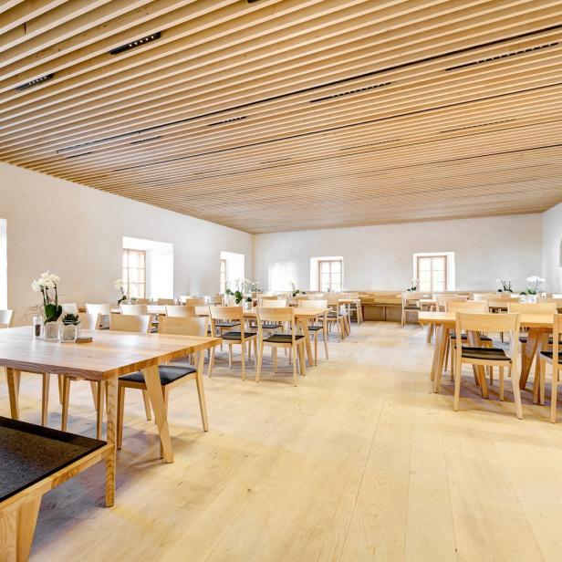 Ein heller Speisesaal mit Holztischen und Stühlen, dekoriert mit Orchideen.