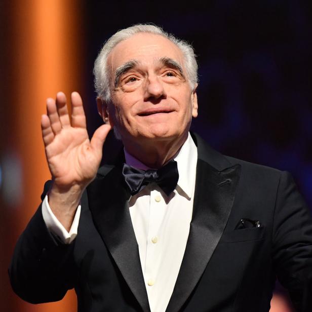 Martin Scorsese in einem Smoking mit Fliege hebt die Hände.