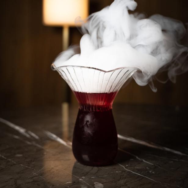 Ein Cocktail in einem Glas mit Trockeneis, das Rauch erzeugt.