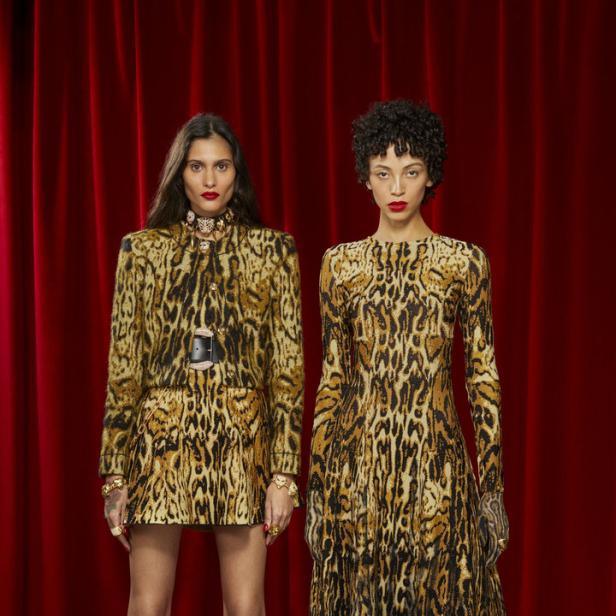 Zwei Models präsentieren Kleidung mit Leopardenmuster vor einem roten Vorhang.