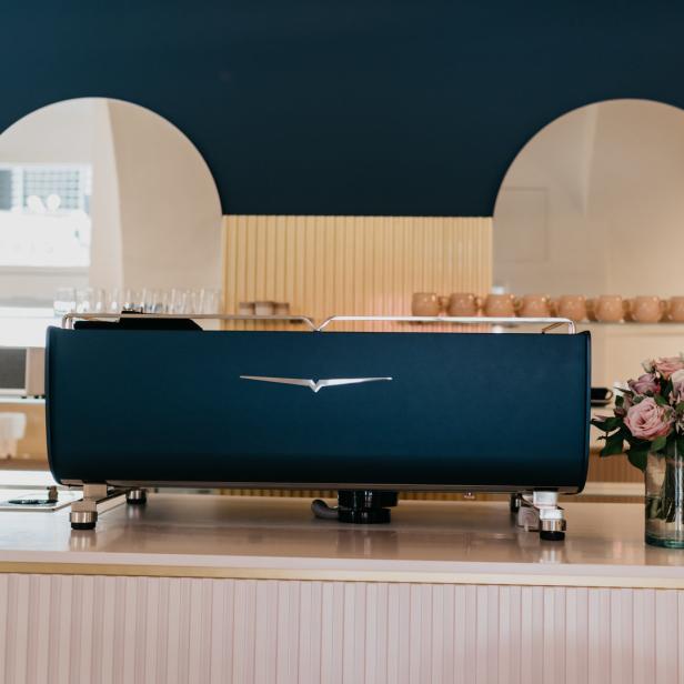 Eine blaue Espressomaschine steht auf einer Theke in einem Café.