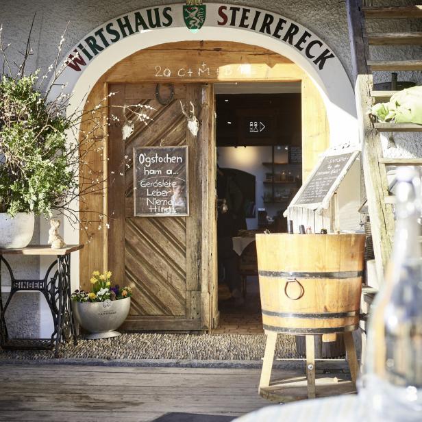 Der Eingang zum „Wirtshaus Steirereck“ mit rustikalen Dekorationen und handgeschriebenen Schildern.