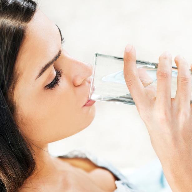 Eine Frau trinkt ein Glas Wasser.