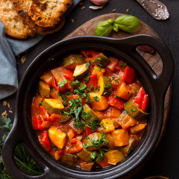 Ein Topf mit Ratatouille, serviert mit geröstetem Brot.