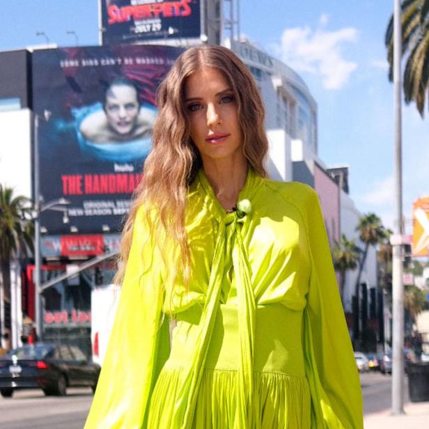 Eine Frau in einem hellgrünen Kleid steht auf einem Bürgersteig in Los Angeles.