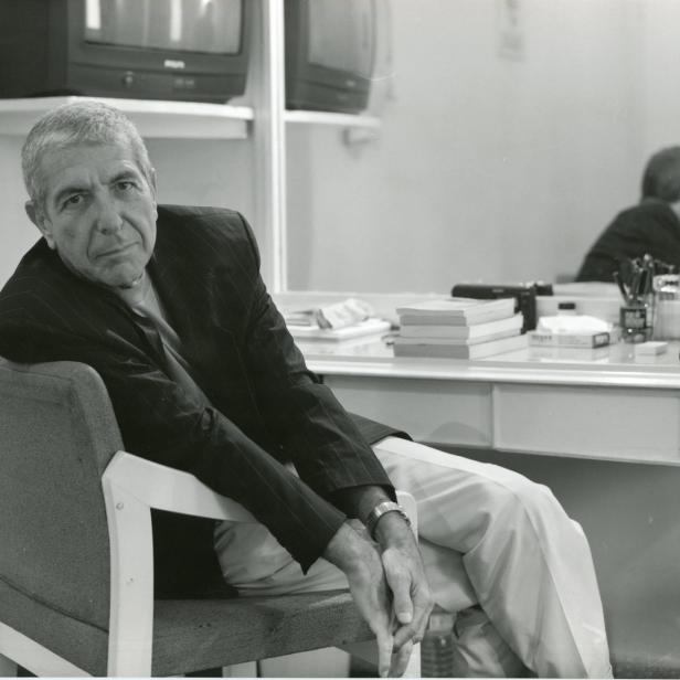 Leonard Cohen sitzt in einem Sessel vor einem Schminktisch mit Spiegel.