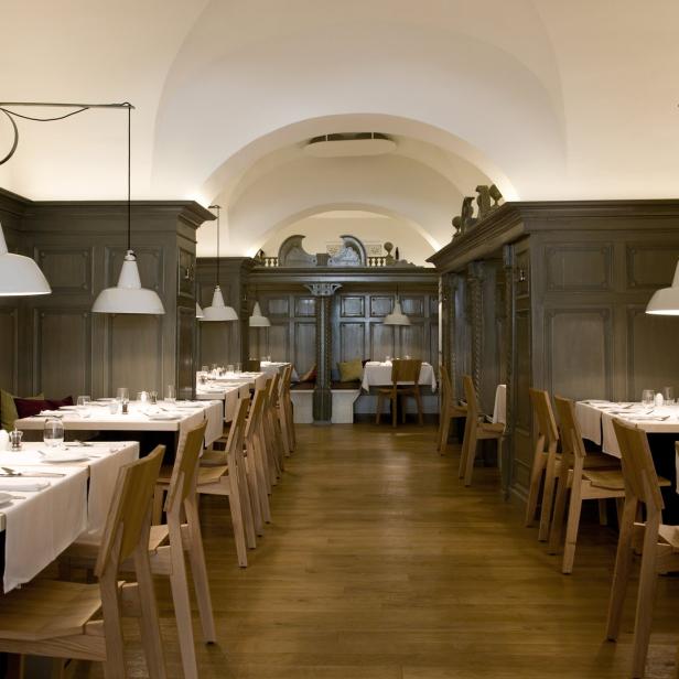 Ein Speisesaal mit gedeckten Tischen und hölzernen Stühlen.