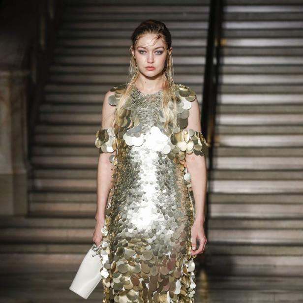 Gigi Hadid trägt ein goldenes Paillettenkleid auf einer Treppe.