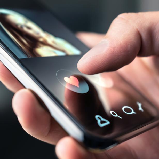 Eine Hand tippt auf einem Smartphone auf ein Herz-Symbol in einer Dating-App.