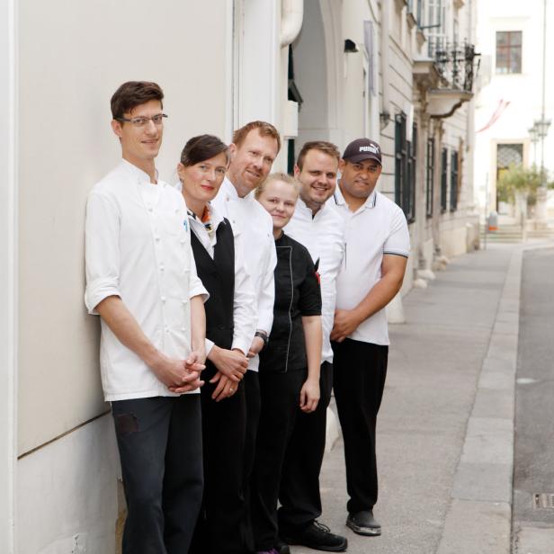 Eine Gruppe von Köchen und Servicepersonal steht vor einem Restaurant.