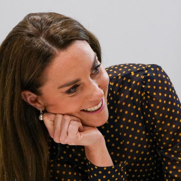 Prinzessin Kate lächelt und stützt ihr Gesicht in ihre Hand.