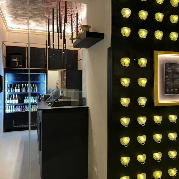 Innenansicht eines modernen Restaurants mit einer Bar und einer Wand mit dekorativen Lichtern.