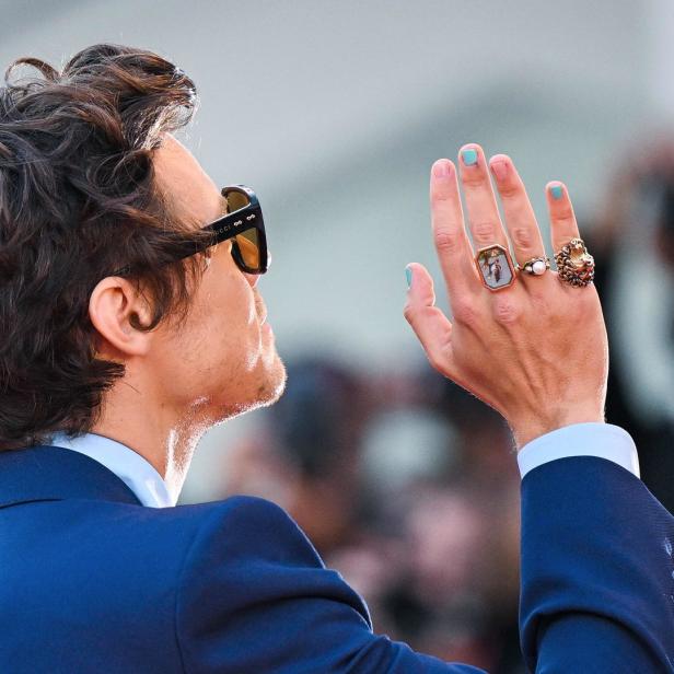 Harry Styles mit Sonnenbrille und mehreren Ringen an der Hand.