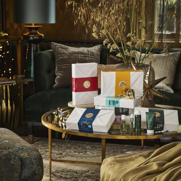 Geschenksets von Rituals stehen auf einem goldenen Tisch in einem Wohnzimmer.
