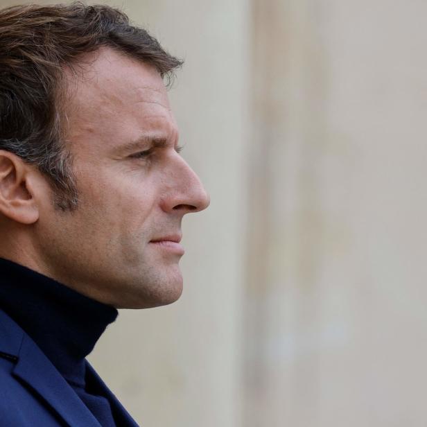 Ein Profilansicht von Emmanuel Macron in einem blauen Anzug.