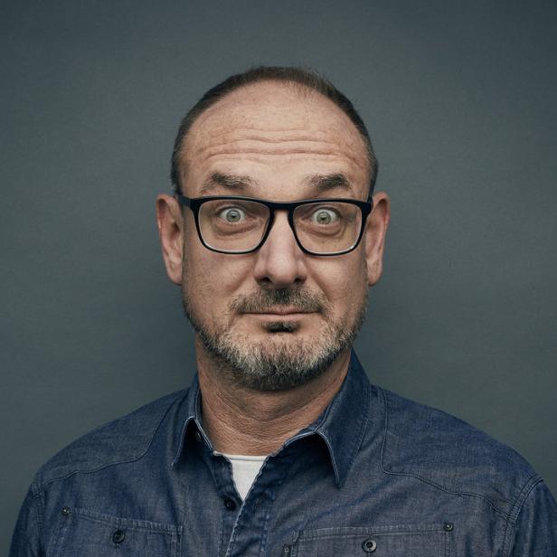 Ein Mann mit Brille und Bart blickt überrascht in die Kamera.