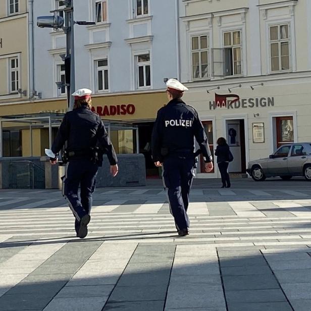 Zwei Polizisten gehen über einen Zebrastreifen in einer Stadt.